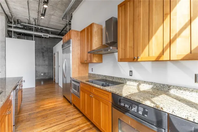 a kitchen with stainless steel appliances granite countertop a refrigerator a sink and a stove