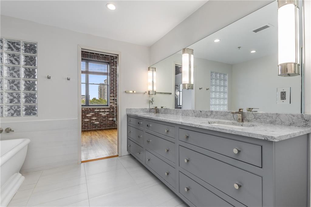 3180 Mathieson Drive Northeast, Unit 1010 Atlanta, GA 30305 - Photo 24 of 44 a bathroom with a granite countertop sink a mirror and a bathtub
