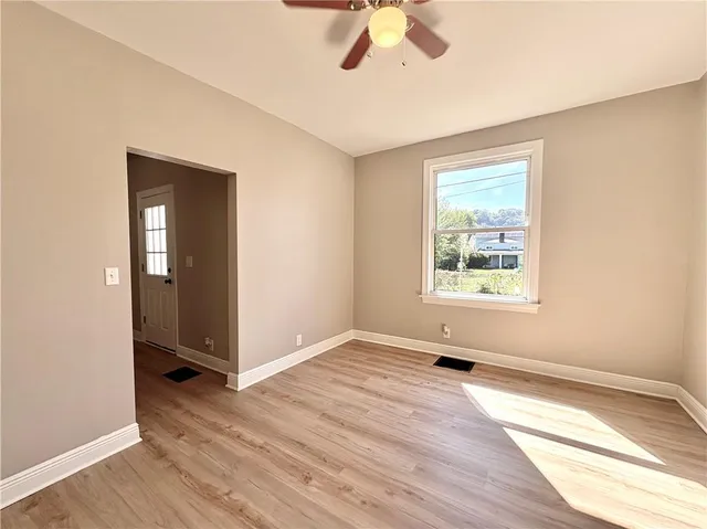 an empty room with wooden floor cabinet and windows