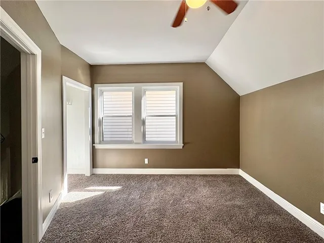 a view of an empty room with chandelier fan and a window