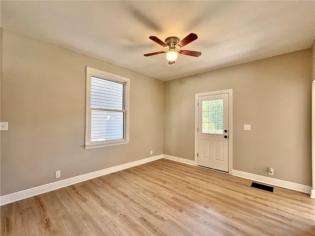 a view of an empty room with wooden floor and a window
