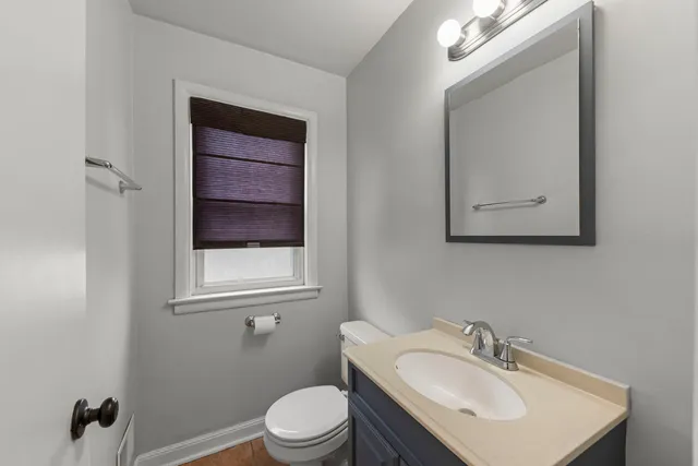 a bathroom with a toilet a sink a mirror and a window