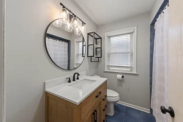 a bathroom with a toilet a sink a mirror and a window