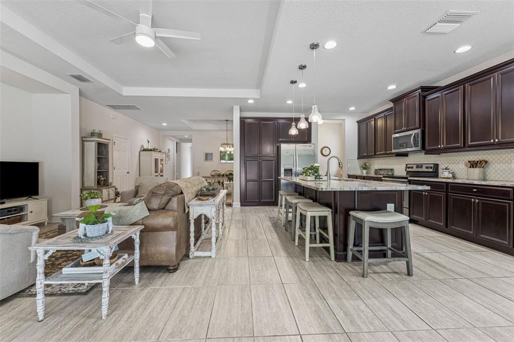 1237 Windy Bay Shoal Tarpon Springs, FL 34689 - Photo 16 of 44 a kitchen with stainless steel appliances kitchen island granite countertop a dining table chairs refrigerator and sink
