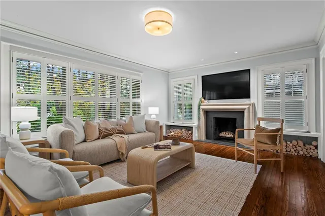 a living room with furniture a floor to ceiling window hardwood floor and a flat screen tv