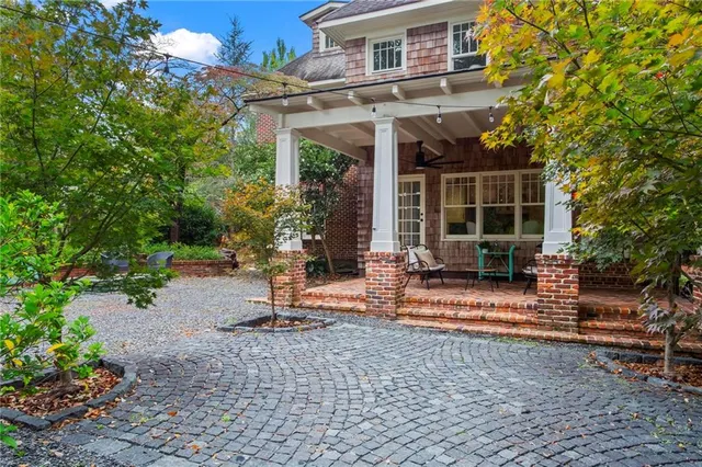 a view of a brick house with plants and large tree