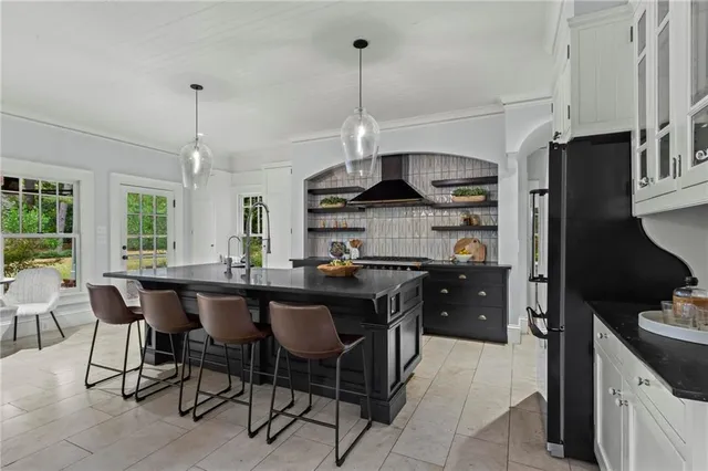 a kitchen with stainless steel appliances granite countertop a sink a stove a refrigerator and chairs