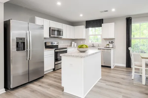 a kitchen with stainless steel appliances a refrigerator a sink a stove a table and chairs