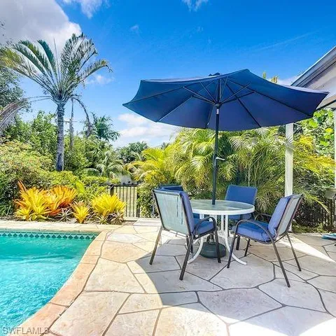 a view of two chairs and table in the garden
