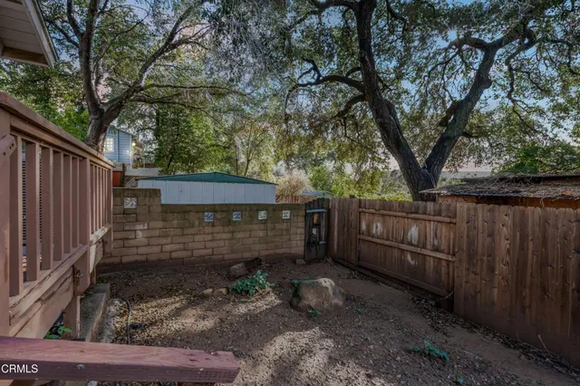 a view of a backyard with wooden fence and large trees