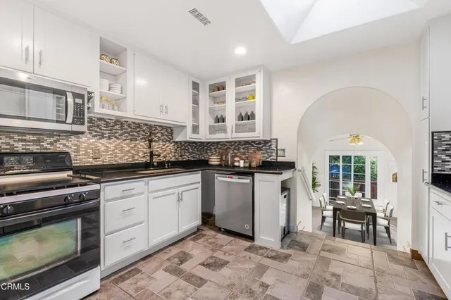 a kitchen with stainless steel appliances granite countertop a stove a sink and a microwave