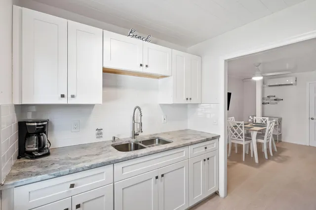 a kitchen with white cabinets and sink