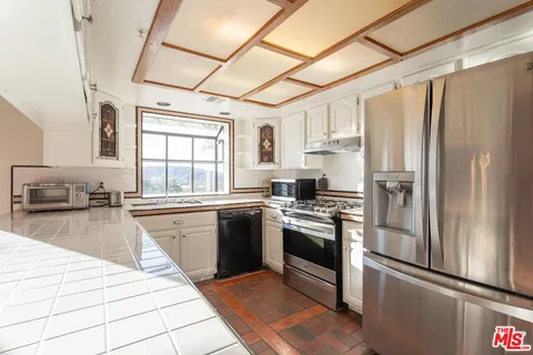 a kitchen with stainless steel appliances granite countertop a refrigerator a sink dishwasher a stove with white cabinets and wooden floor