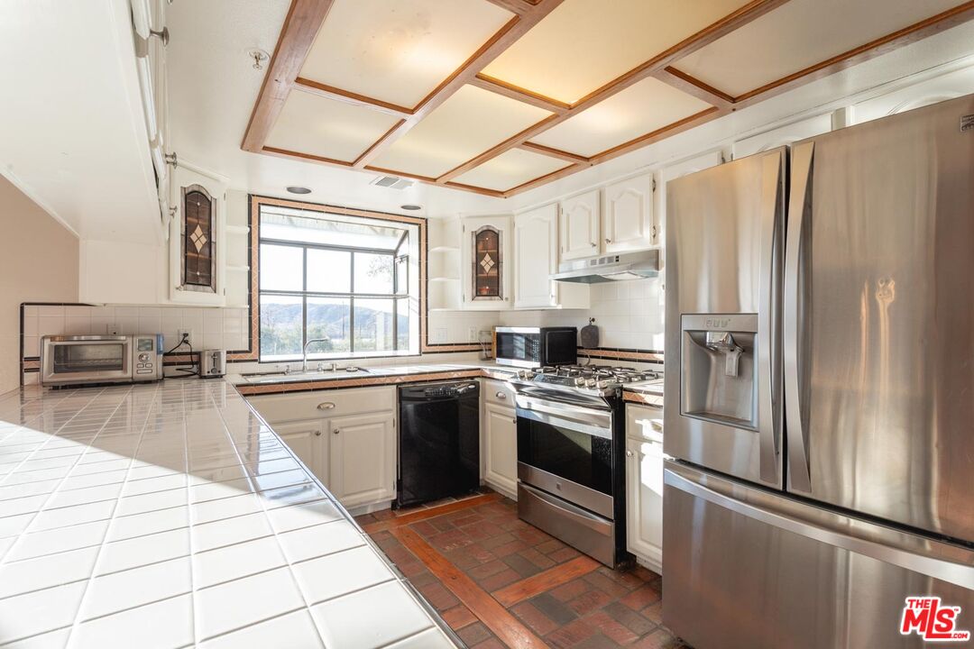 29243 Piani Road Pearblossom, CA 93553 - Photo 11 of 64 a kitchen with stainless steel appliances granite countertop a refrigerator a sink dishwasher a stove with white cabinets and wooden floor