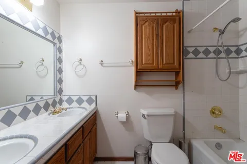 a bathroom with a granite countertop toilet sink and mirror
