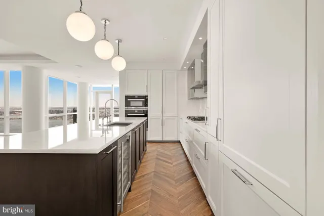 a large kitchen with kitchen island white cabinets and stainless steel appliances