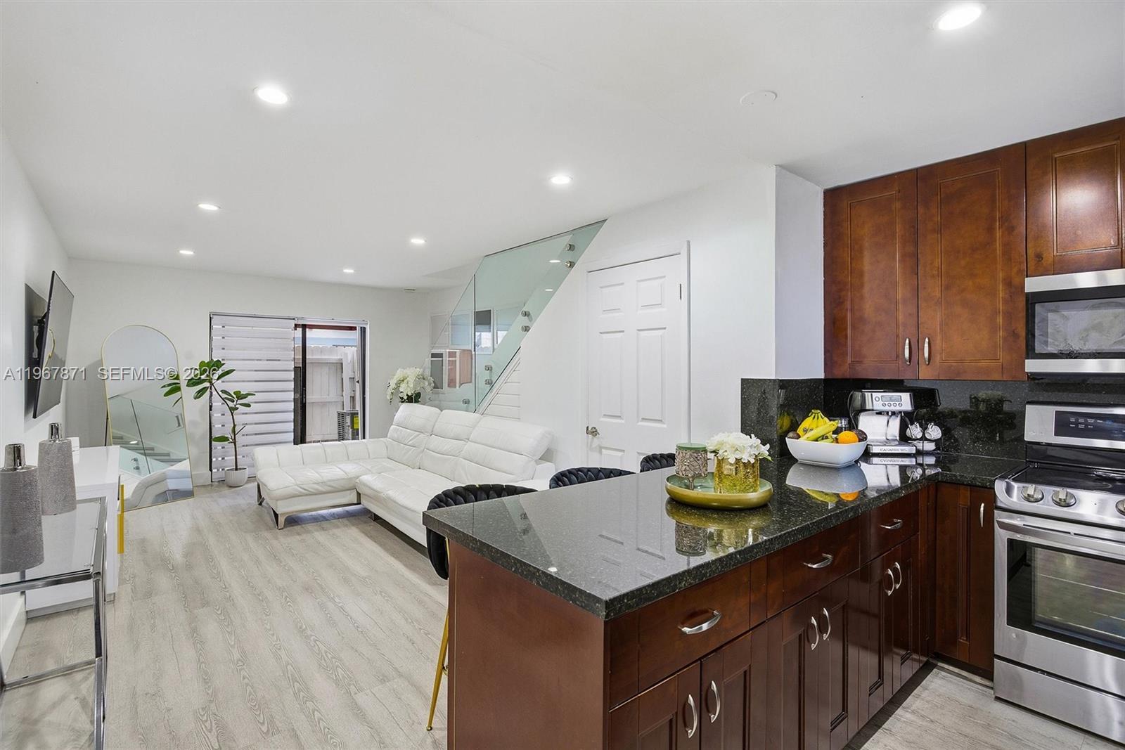 11781 Southwest 18th Street, Unit 640 Miami, FL 33175 - Photo 4 of 32 a kitchen with stainless steel appliances a sink a stove a refrigerator cabinets and living room view