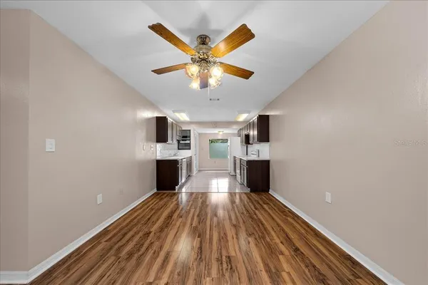 a large white kitchen with a sink and dishwasher a stove top oven with wooden floor