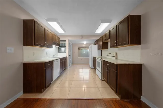 a large white kitchen with a sink stainless steel appliances and cabinets