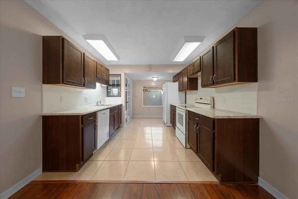 3702 Northeast 17th Street Ocala, FL 34470 - Photo 9 of 63 a large kitchen with stainless steel appliances kitchen island granite countertop a stove top oven a sink dishwasher and a microwave oven with wooden floor