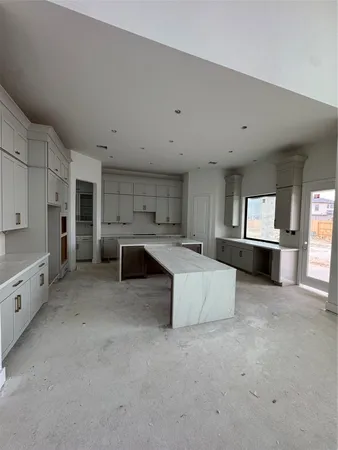 a large white kitchen with granite countertop a large window