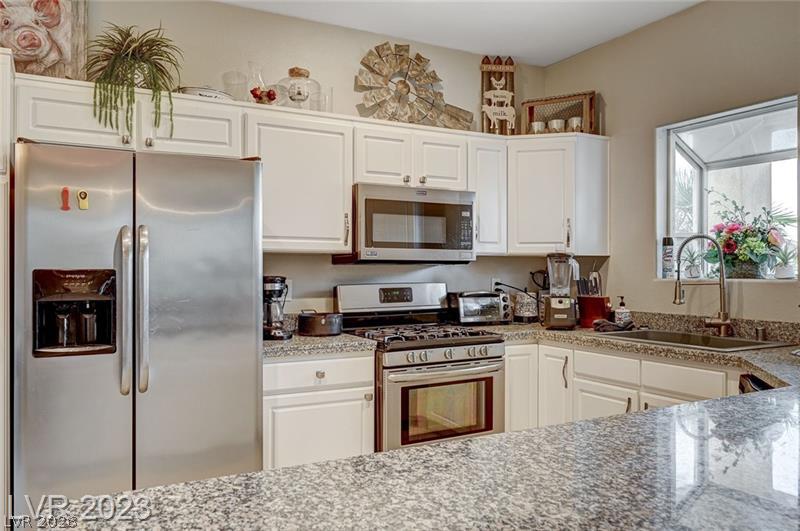 987 Cutter Street Henderson, NV 89011 - Photo 6 of 17 Prepare meals in this kitchen featuring white cabinetry and granite counters.