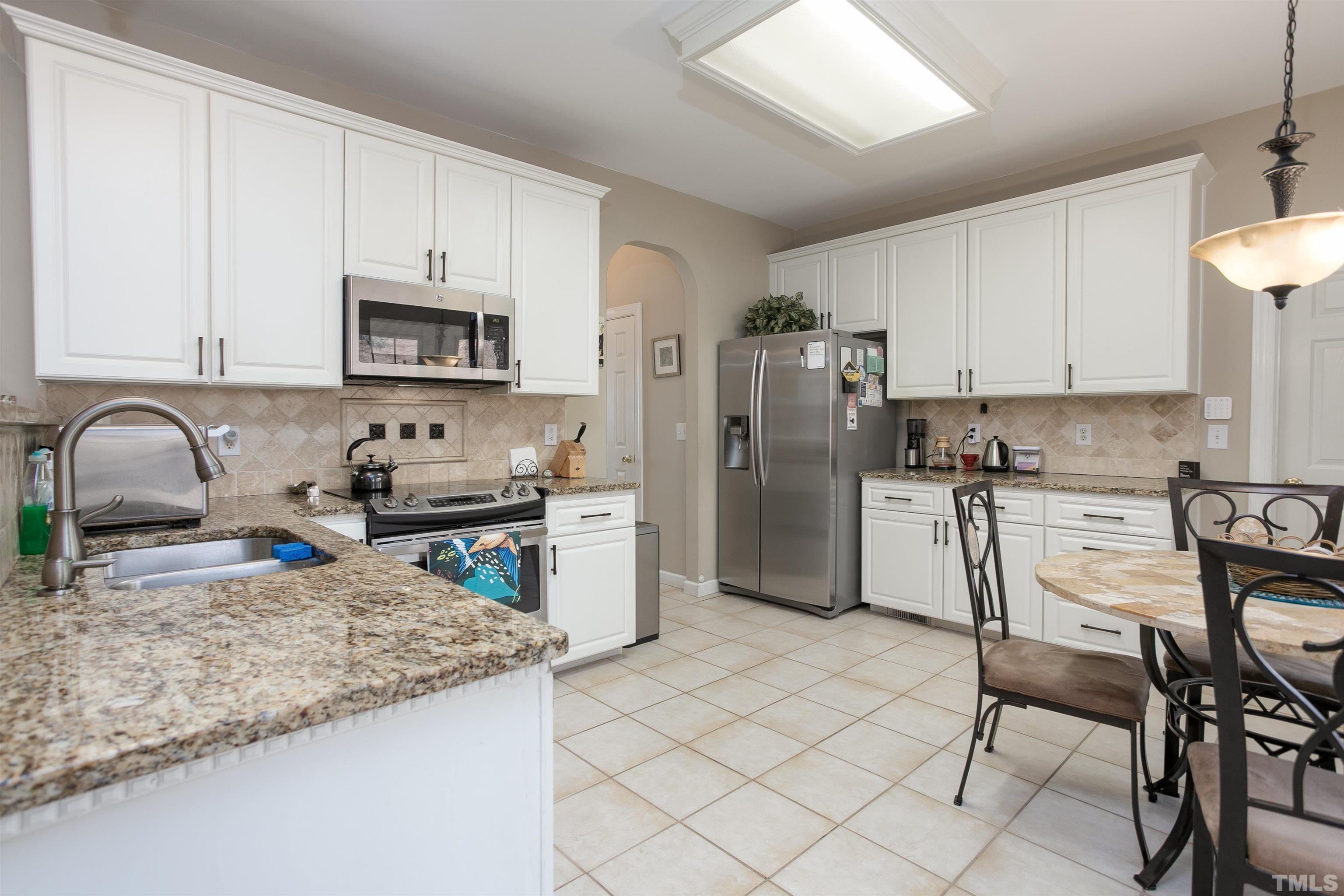 8832 Braceridge Road Raleigh, NC 27613 - Photo 17 of 40 a kitchen with stainless steel appliances granite countertop a sink a stove a microwave and a refrigerator