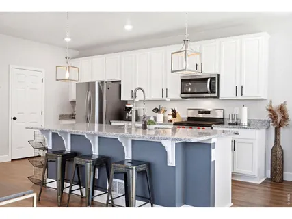 a kitchen with stainless steel appliances a table chairs refrigerator and microwave