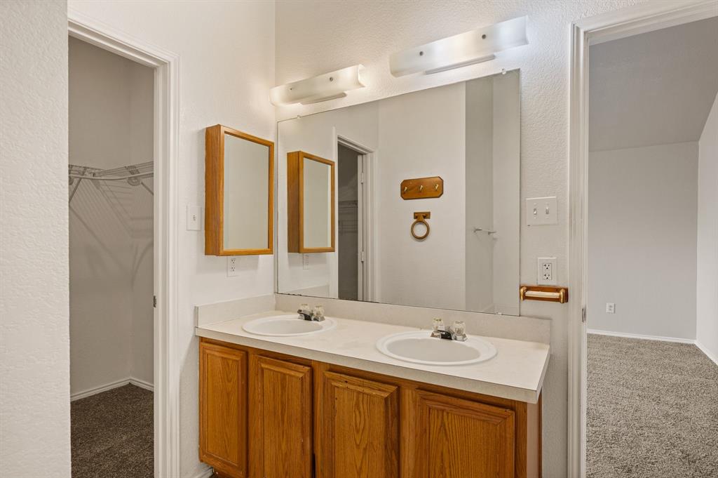 5509 Timber Ridge Court Watauga, TX 76137 - Photo 25 of 28 Dual vanity with wood-finish cabinetry and a large wall-mounted mirror