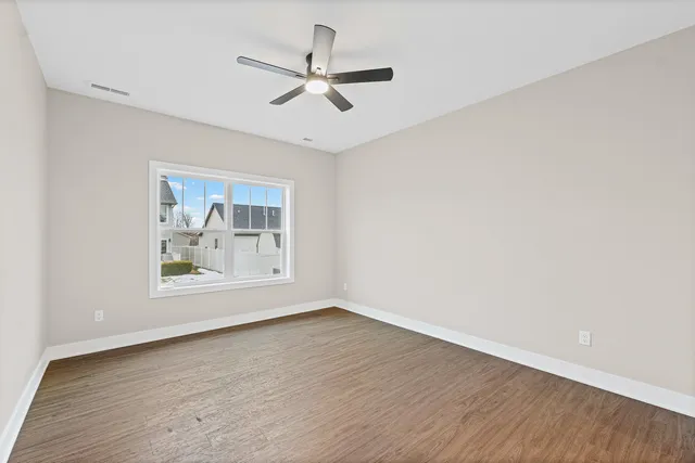 an empty room with wooden floor and a ceiling fan