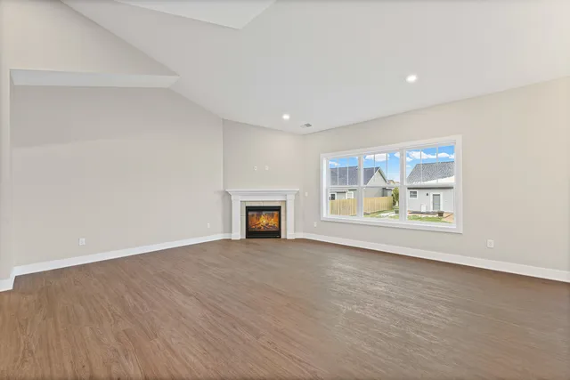 an empty room with fireplace and wooden floor