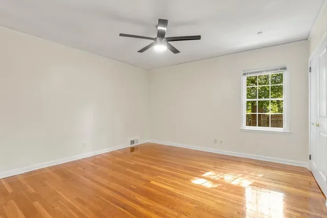 an empty room with a window and ceiling fan