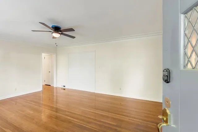 an empty room with wooden floor fan and windows
