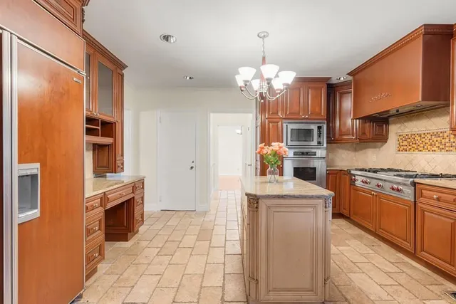 a kitchen with stainless steel appliances granite countertop a refrigerator a stove and a sink with chandelier