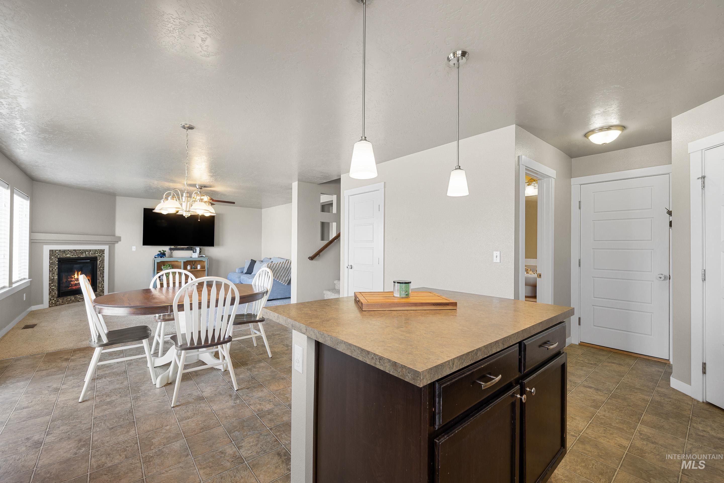 700 Southwest Panner Street Mountain Home, ID 83647 - Photo 50 of 50 Kitchen with dark wood finish cabinets, open floor plan, decorative light fixtures, a tiled fireplace, and a kitchen island