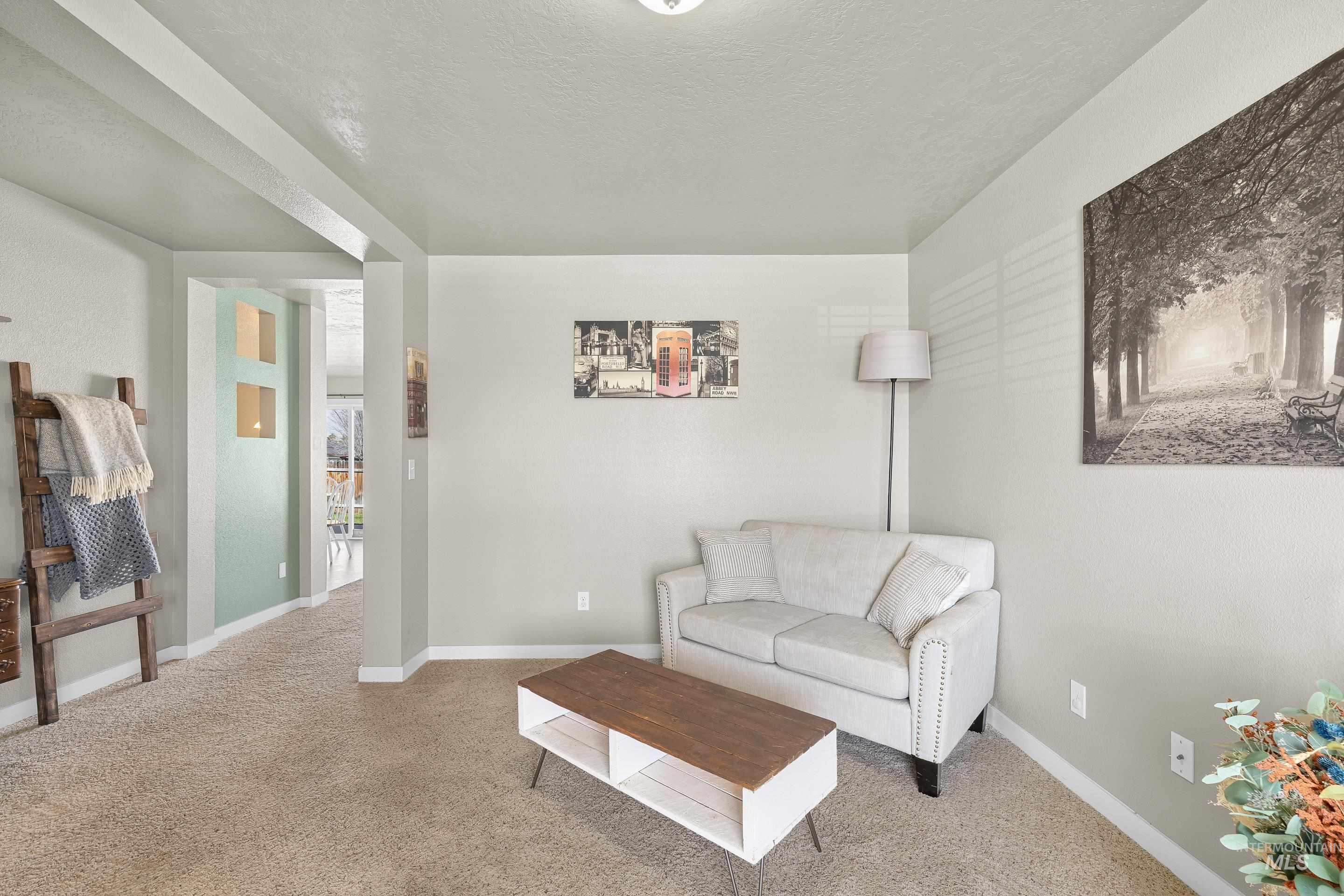 700 Southwest Panner Street Mountain Home, ID 83647 - Photo 27 of 50 Carpeted living room featuring baseboards and a textured ceiling