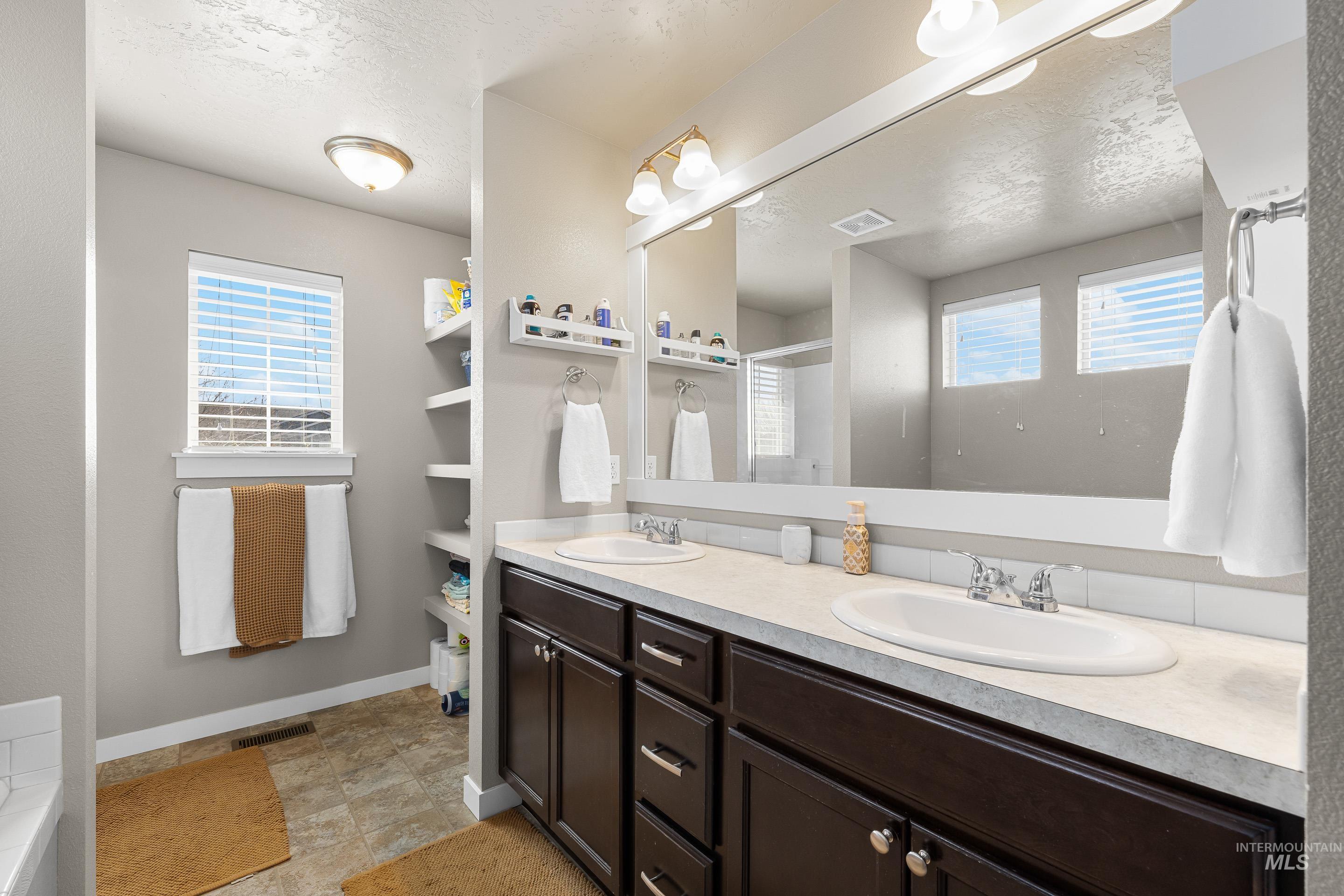 700 Southwest Panner Street Mountain Home, ID 83647 - Photo 33 of 50 Full bath with double vanity, a textured ceiling, a shower stall, and stone finish flooring