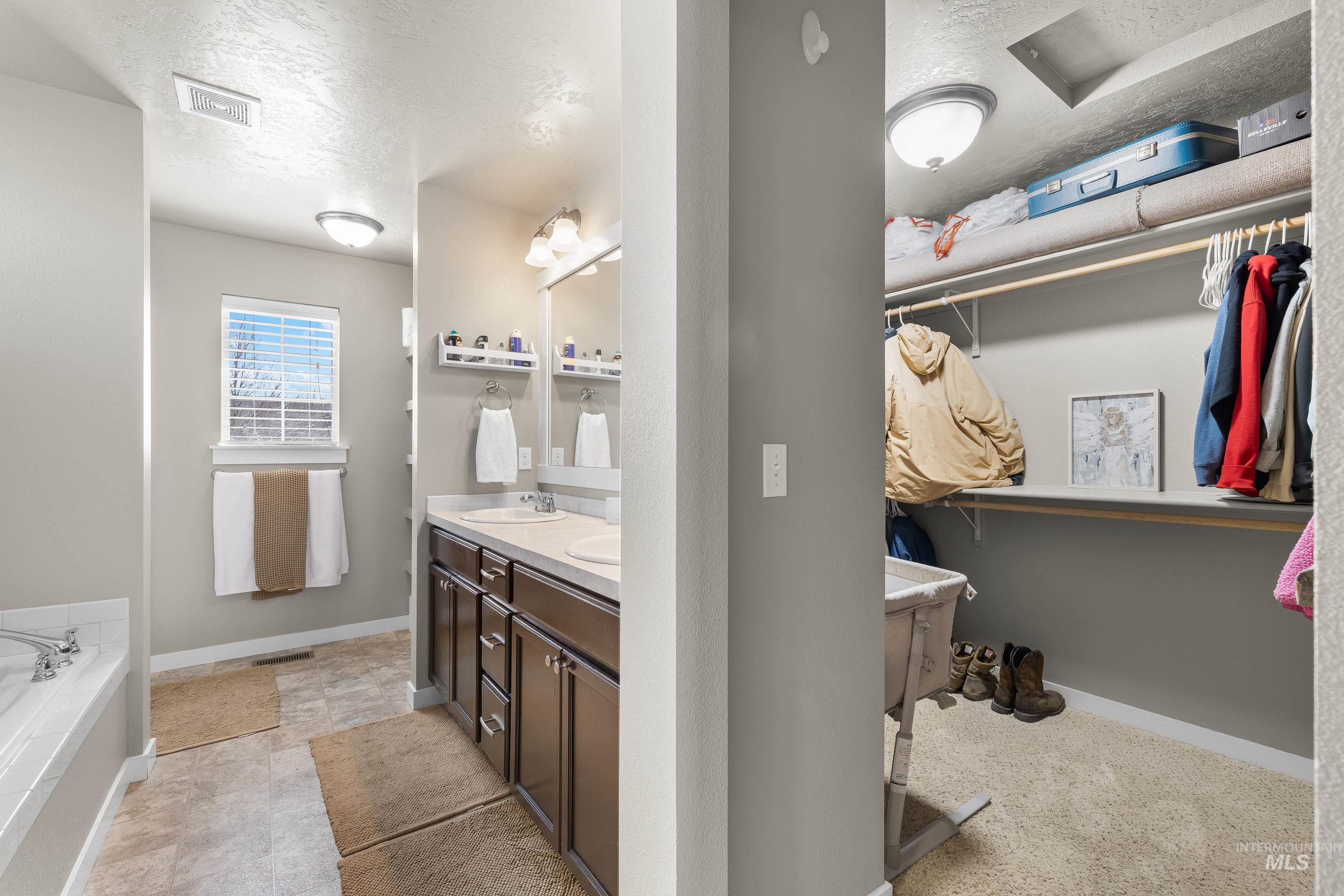 700 Southwest Panner Street Mountain Home, ID 83647 - Photo 35 of 50 Full bathroom with a spacious closet, a textured ceiling, double vanity, and a garden tub