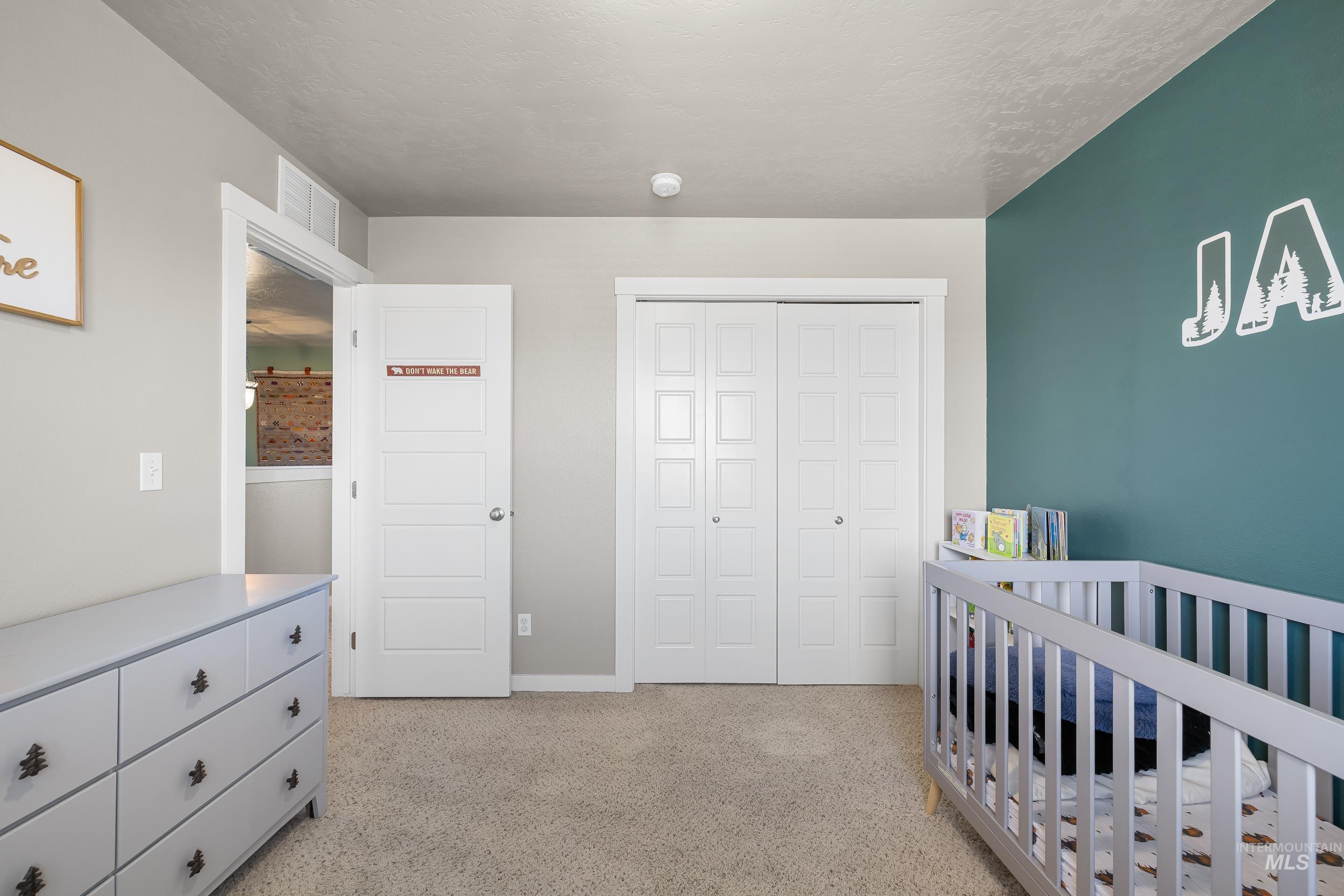 700 Southwest Panner Street Mountain Home, ID 83647 - Photo 43 of 50 Bedroom featuring a crib, light colored carpet, a closet, and a textured ceiling