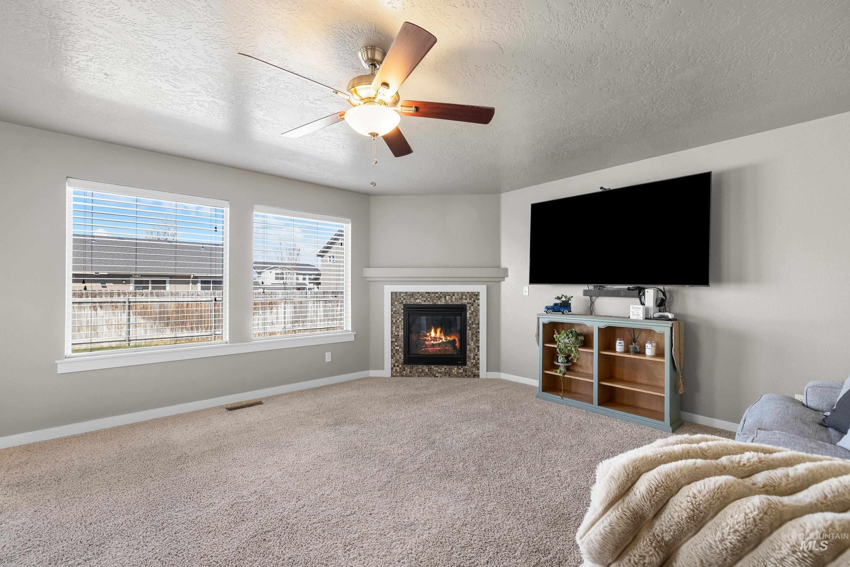 700 Southwest Panner Street Mountain Home, ID 83647 - Photo 8 of 50 Living area with carpet, a fireplace, a ceiling fan, and a textured ceiling