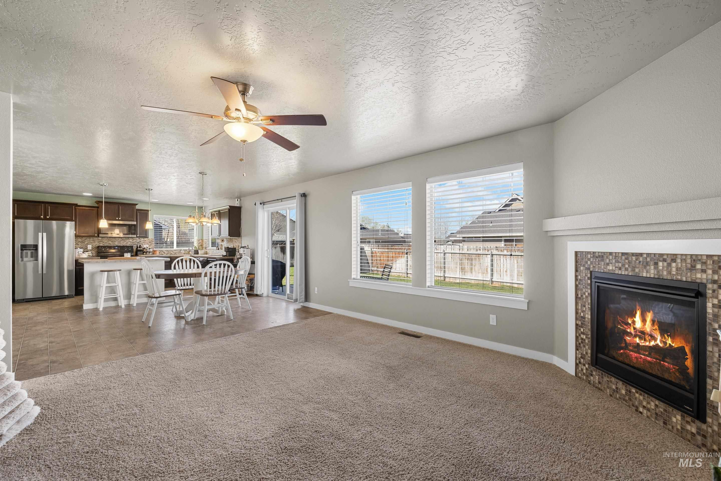 700 Southwest Panner Street Mountain Home, ID 83647 - Photo 10 of 50 Living room with a fireplace, a textured ceiling, dark colored carpet, and plenty of natural light