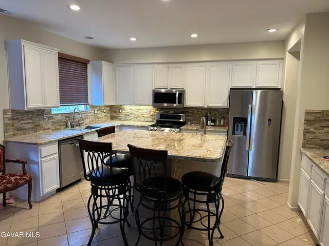 a kitchen with stainless steel appliances a table chairs refrigerator a sink and a stove