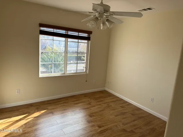 an empty room with wooden floor fan and windows
