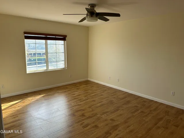 an empty room with wooden floor cabinet and windows