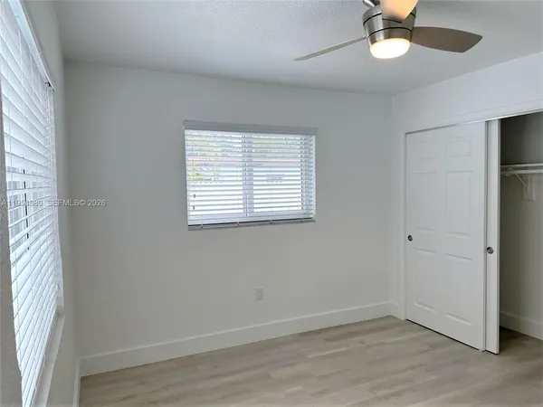 an empty room with a window and a fan