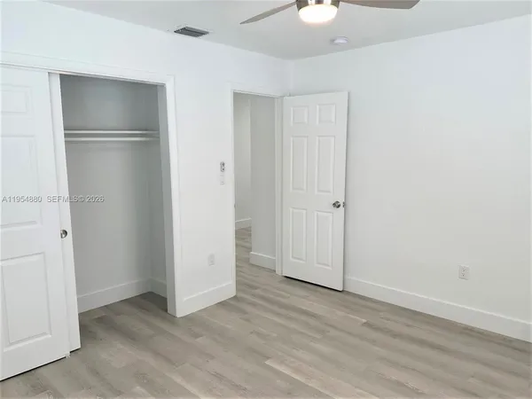 an empty room with wooden floor and closet area