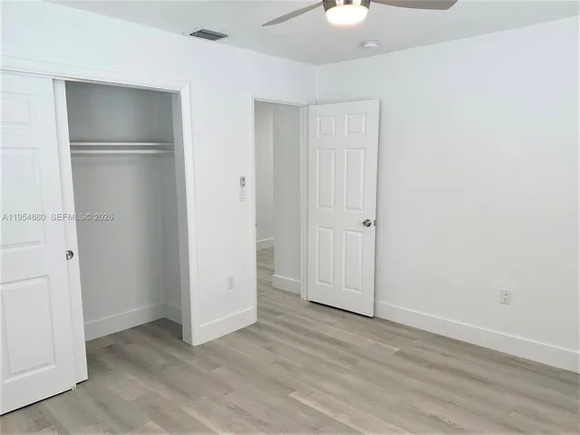 an empty room with wooden floor and closet area