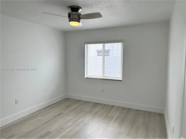 a view of empty room with window and wooden floor