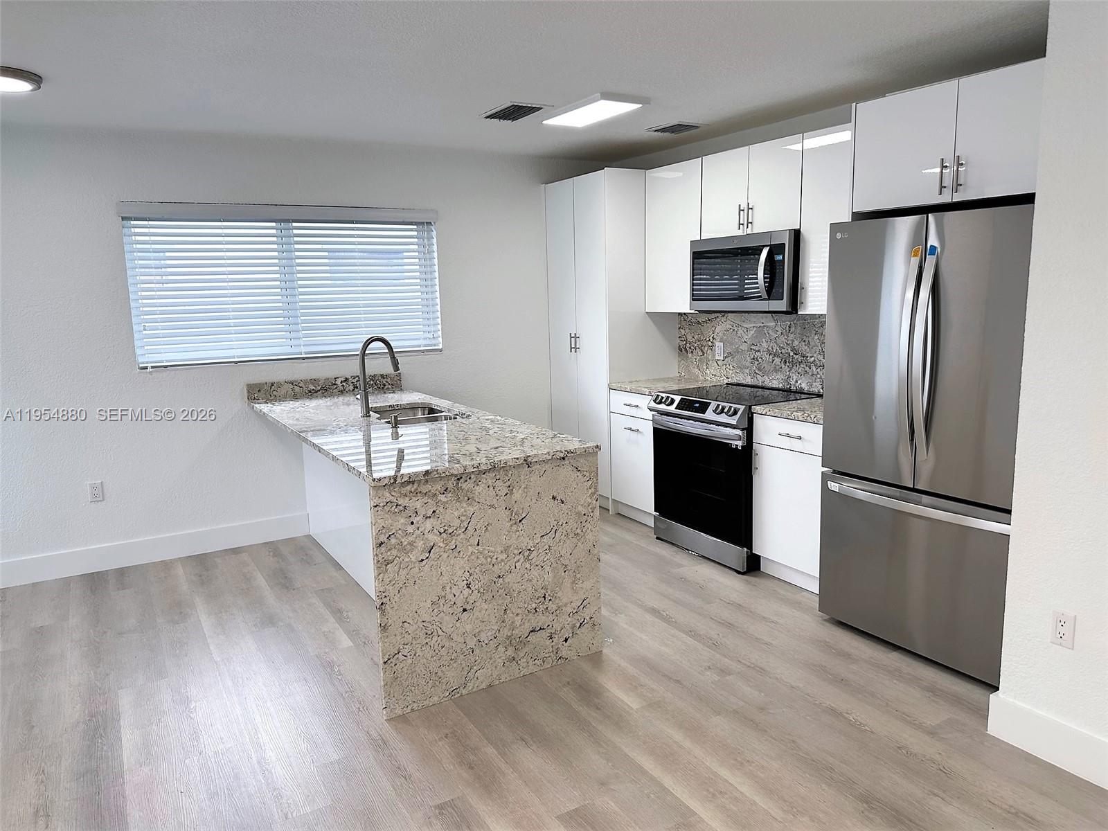 11230 Southwest 5th Street, Unit 1 Sweetwater, FL 33174 - Photo 4 of 25 a kitchen with stainless steel appliances granite countertop a refrigerator a stove a sink and a microwave