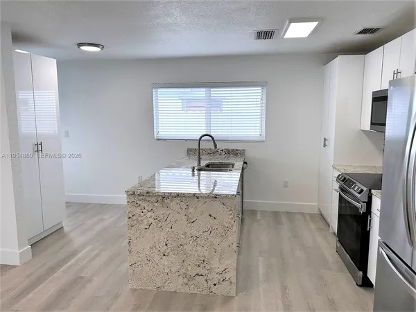 a kitchen with granite countertop a sink stove and refrigerator